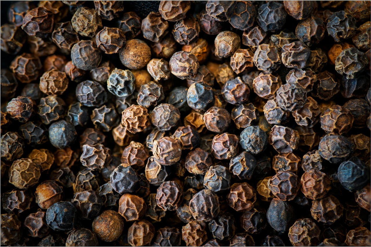 Rich texture and detail of whole black peppercorns in a macro shot.